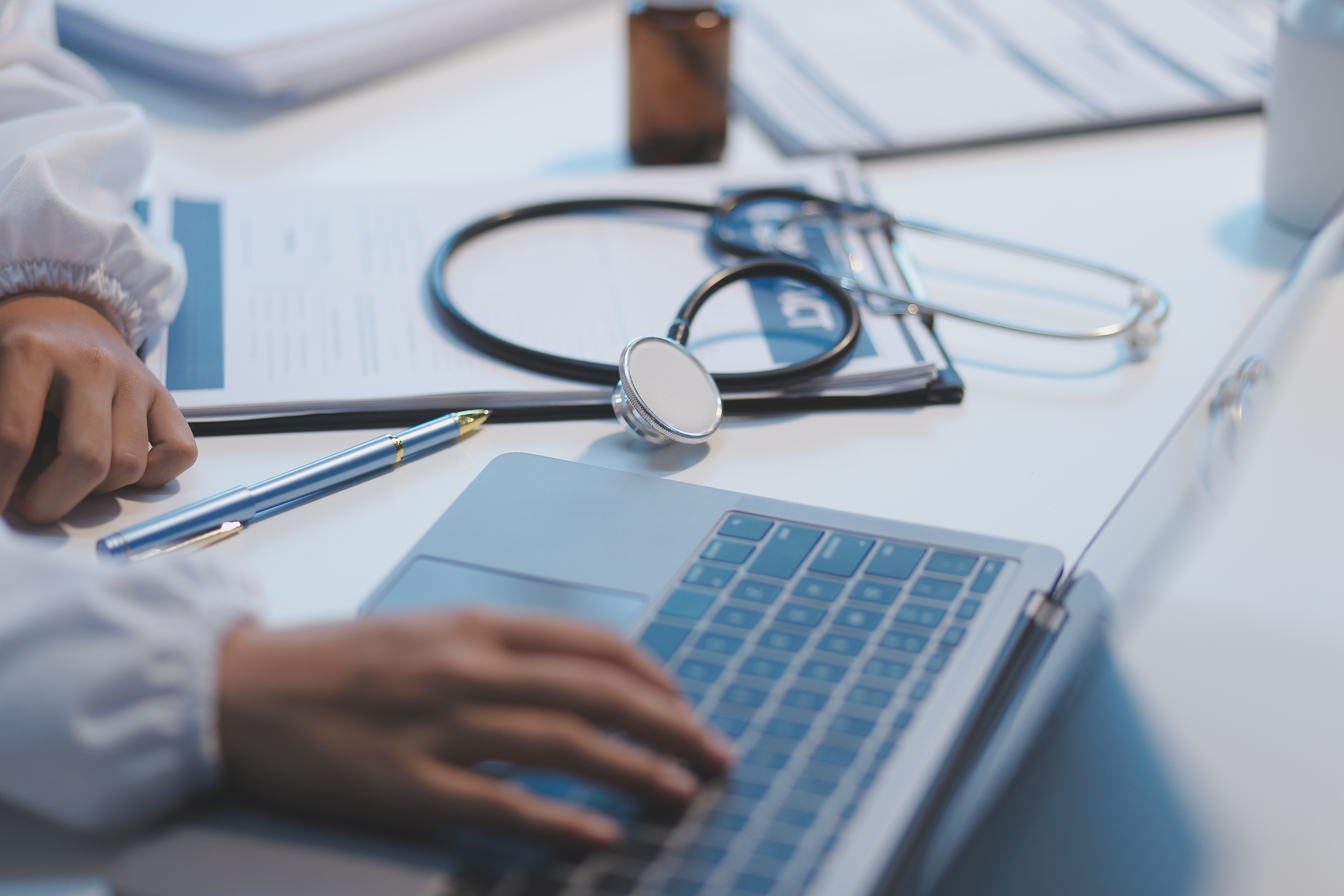 person with hand on laptop in medical setting